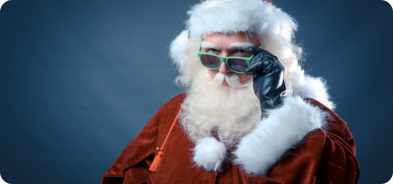 Père Noël en tenue rouge classique, portant des lunettes vertes et un gant noir, regardant avec un air malicieux